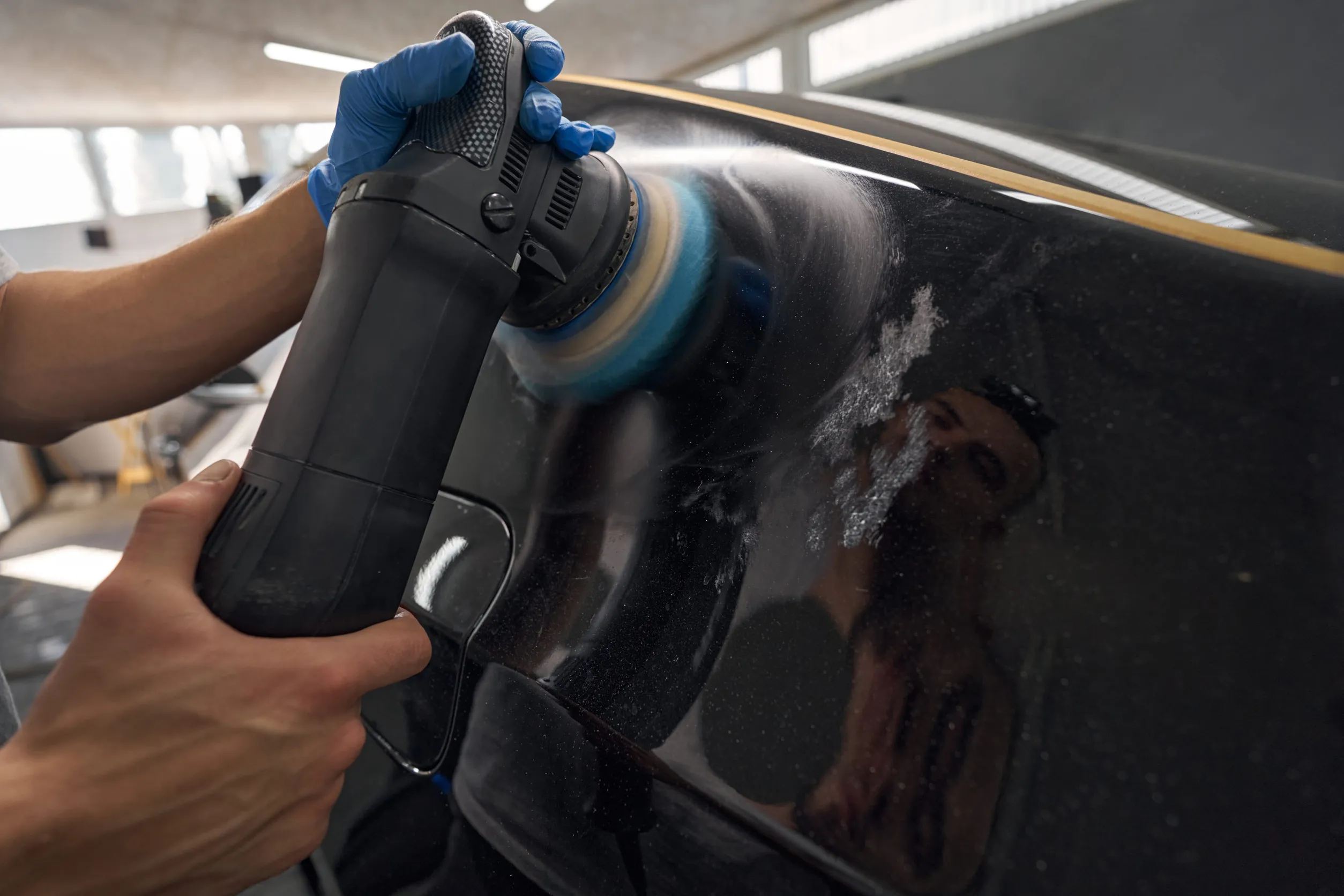 Hands with orbital polisher in auto repair shop